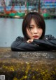 A woman leaning against a wall with her arms crossed.