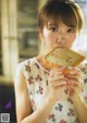 A young woman eating a piece of bread.