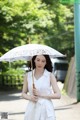 A woman in a white dress holding an umbrella.