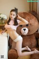 A woman sitting on a couch next to a teddy bear.