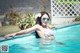 A woman in a bikini and sunglasses in a swimming pool.