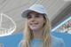 A woman wearing a white hat smiles at the camera.